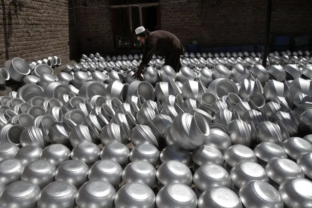 An Afghan laborer arranges pots at an aluminum factory, on Surkh Rod district of Jalalabad east of Kabul, Afghanistan, Wednesday, June 5, 2013. Men working at the factory earn an average of 400 AFN ($ 7.28 cents) per day. (Photo by Rahmat Gul/AP Photo)