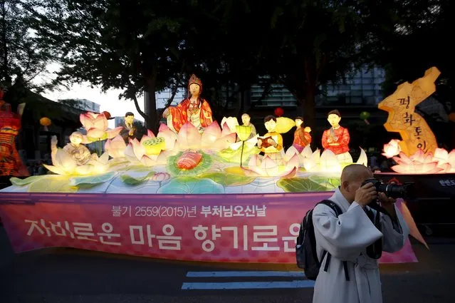 A buddhist monk takes photographs during a lotus lantern parade in celebration of the upcoming birthday of Buddha in Seoul, South Korea, May 16, 2015. Buddha's birthday is commemorated on May 25 in South Korea. (Photo by Kim Hong-Ji/Reuters)