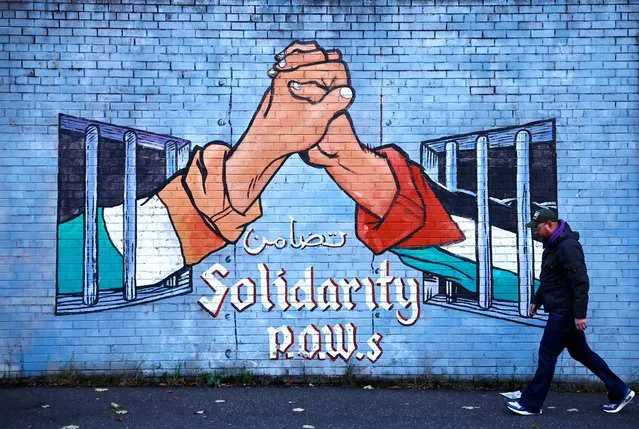 A man walks past a mural in solidarity with Palestinians in Gaza, amid the ongoing conflict between Israel and Hamas, in the Nationalist area along the International Wall on the Falls Road in Belfast, Northern Ireland, on November 4, 2023. (Photo by Clodagh Kilcoyne/Reuters)