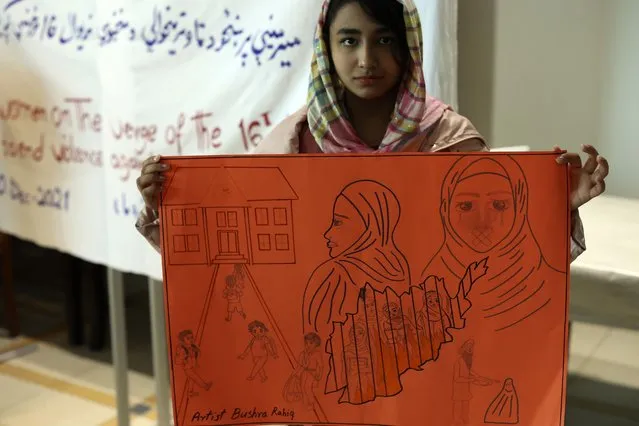 An Afghan girl holds a sketch during a public awareness meeting on violence against women, at a coastline tourist resort in Golem, 50 kilometers (30 miles) west of Tirana, Albania, Friday, December 10, 2021. Afghan women evacuated to Albanian after the Taliban came to power in August have made a loud call to the international community to pay attention to their female brethren back at home who are harshly discriminated. (Photo by Franc Zhurda/AP Photo)