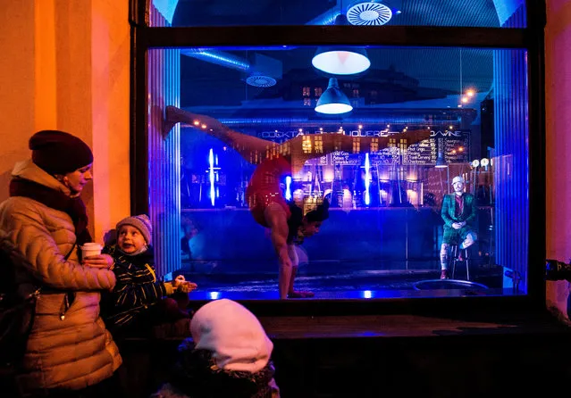People watch a performance of members of the new circus company Cirk La Putyka in a pub window on January 21, 2021 in Prague as support of the culture sector hit by the pandemic of COVID -19. (Photo by Michal Cizek/AFP Photo)