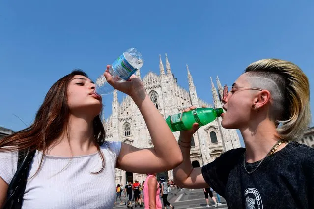 Women drink water in front of the Duomo in central Milan during a heatwave on June 26, 2019. Meteorologists blamed a blast of torrid air from the Sahara for the unusually early summer heatwave, which could send thermometers up to 40 degrees Celsius (104 Fahrenheit) in some places on June 27 and 28. Experts say such heatwaves early in the summer are likely to be more frequent as the planet heats up (Photo by Miguel Medina/AFP Photo)
