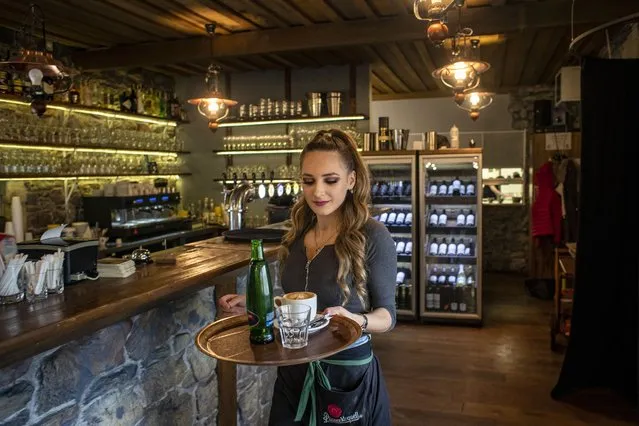 A waitress brings drinks to customers at Seberak restaurant in Prague, Czech Republic, 04 February 2021. Jakub Olbert, owner of Seberak restaurant and co-founder of Chcipl pes movement, opened his restaurant in protest against Czech government's coronavirus measures. The Czech government decided all restaurants closed from 18 December 2020 due to restrictions in connection with the COVID-19 pandemic caused by the SARS-CoV-2 coronavirus. (Photo by Martin Divisek/EPA/EFE)