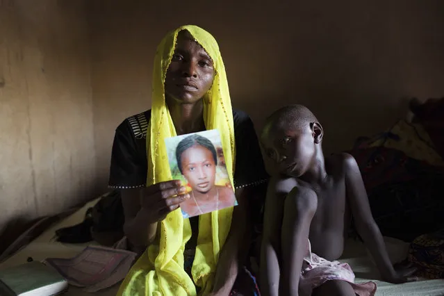 Rachel Daniel, 35, holds up a picture of her abducted daughter Rose Daniel, 17, as her son Bukar, 7, sits beside her at her home in Maiduguri May 21, 2014. Rose was abducted along with more than 250 of her classmates on April 14 by Boko Haram militants from a secondary school in Chibok, Borno state. (Photo by Joe Penney/Reuters)