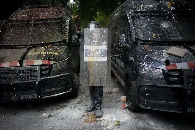 Riot police officers covered by paint and powder thrown by protesters stand guard as activists gather to stop the eviction of Axel Altadill, 28 from his apartment in Barcelona, Spain, Tuesday, May 25, 2021. Mr. Altadill has been accused of squatting in the apartment since January 2019. (Photo by Joan Mateu/AP Photo)