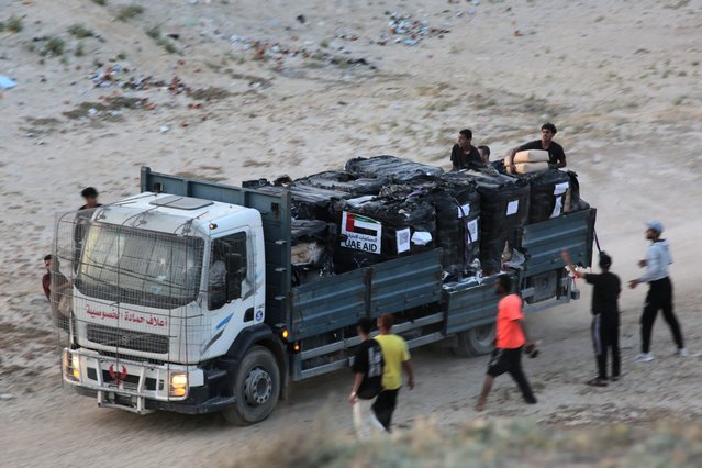 Palestinians rush a truck as it transports international humanitarian aid from the US-built Trident Pier near Nuseirat in the central Gaza Strip on May 18, 2024, amid the ongoing conflict between Israel and the militant group Hamas. (Photo by AFP Photo/Stringer)
