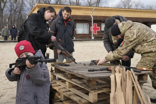 A boy plays with a weapon as an instructor shows a Kalashnikov assault rifle while training members of a Ukrainian far-right group train, in Kyiv, Ukraine, Sunday, February 20, 2022. Russia extended military drills near Ukraine's northern borders Sunday amid increased fears that two days of sustained shelling along the contact line between soldiers and Russia-backed separatists in eastern Ukraine could spark an invasion. (Photo by Efrem Lukatsky/AP Photo)