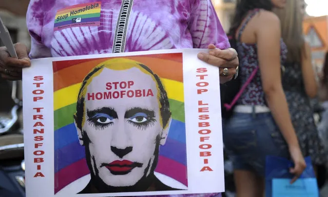 A demonstrator holds a poster depicting Russian President Vladimir Putin with make-up as he protests against homophobia and repression against gays in Russia, outside the Ministry of Foreign Affairs and Cooperation in Madrid on  September 3, 2013. Russia has added a digitally altered image of President Vladimir Putin in heavy makeup to its list of banned extremist materials, saying the picture suggests Putin is gay.  (Photo by Curto De La Torre/AFP Photo)