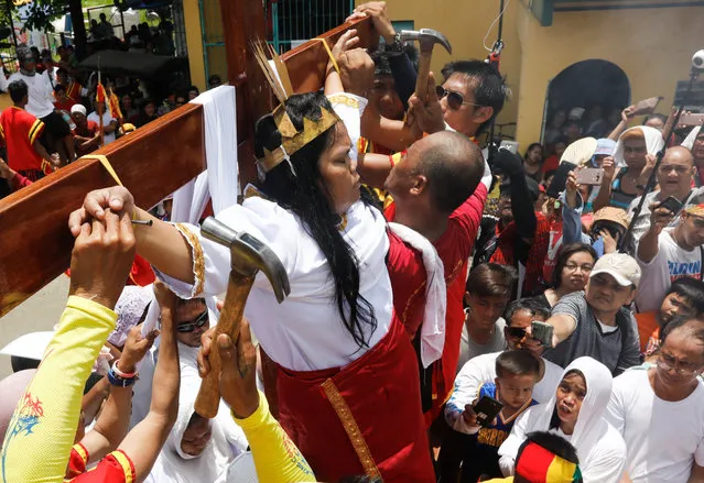 Filipino female penitent Precy Valencia is nailed to a wooden cross for the thirteenth year as spectators watch in Paombong District of Malolos, Bulacan Province, north of Manila, Philippines, 14 April 2017. During Lent season many Catholics continue to subject themselves to several forms of self-inflicted pain such as crucifixion on Good Friday as a sign of faith and to seek forgiveness for their sins, despite calls from the Catholic Church to refrain from doing physical forms of penance. (Photo by Rolex Dela Pena/EPA)