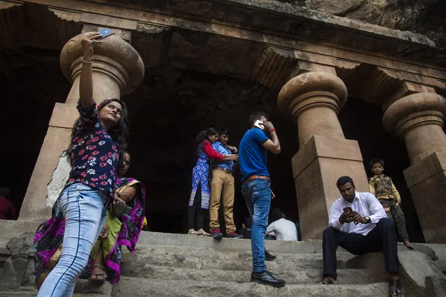 People walk around, take photos, make phone calls, and admire the large carvings in the Elephanta Caves, a UNESCO World Heritage Centre and contain a collection of rock art linked to the cult of Shiva, on Elephanta Island in Navi Mumbai, India on Tuesday May 10, 2016. (Photo by Jabin Botsford/The Washington Post)