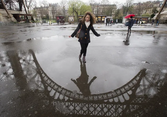 Tourist identified only as Leletskee, from New York, USA, looks at the Eiffel Tower's reflection of the pavement in Paris , Thursday, March 31, 2016. Paris' Eiffel tower is closed all day. The company operating the monument said in a statement there are not enough staff to open the tower with “sufficient security and reception conditions”. (Photo by Jacques Brinon/AP Photo)