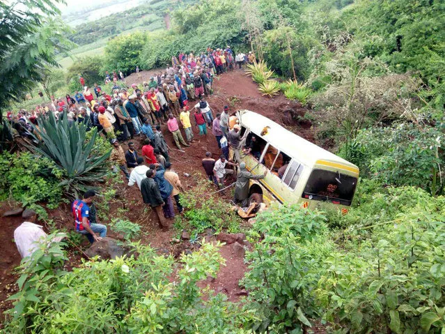 Residents gather at the scene of an accident that killed schoolchildren, teachers and a minibus driver at the Rhota village along the Arusha-Karatu highway in Tanzania's northern tourist region of Arusha, May 6, 2017. (Photo by Emmanuel Herman/Reuters)