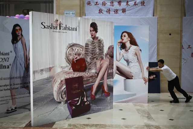 A man pushes a fashion advertisement billboard outside a fashion boutique under renovation at Ritan International Trade Center in Beijing, Monday, May 8, 2017. China has reported its exports expanded for a second straight month in April but at a slower pace while import growth also decelerated as demand cooled both at home and overseas. (Photo by Andy Wong/AP Photo)