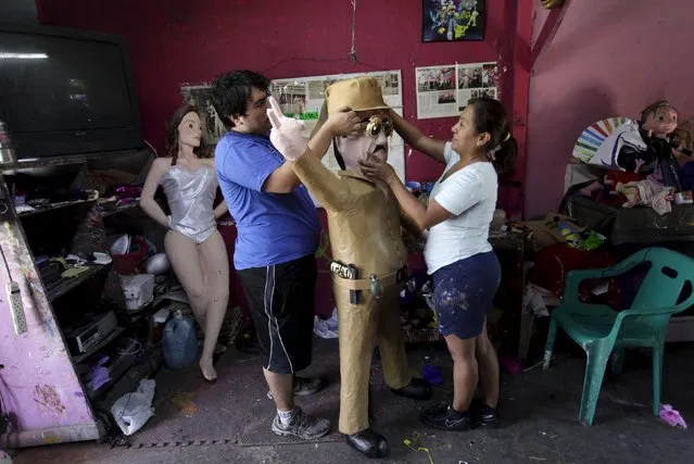 Workers attach a hat to a pinata depicting the drug lord Joaquin “El Chapo” Guzman at a workshop in Reynosa, July 21, 2015. (Photo by Daniel Becerril/Reuters)