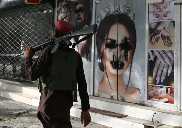 In this file photo taken on August 18, 2021, a Taliban fighter walks past a beauty salon with images of women defaced using spray paint in Shar-e-Naw in Kabul. US President Joe Biden said in an interview that aired August 19, 2021, that war is not the answer to growing fears for the human rights of women in Afghanistan after the Taliban takeover. “The idea that we're able to deal with the rights of women around the world by military force is not rational”, Biden said in the ABC News interview, his first since the Taliban victory triggered a frantic final US withdrawal. (Photo by Wakil Kohsar/AFP Photo)