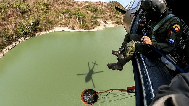 This handout picture released by the Colombian Air Force on May 30, 2023, shows members of the Air Force refilling water in a helicopter to fight a wildfire at The Peak Natural Park in Providencia, Colombia. The Peak Natural Park, one of the most important in the Colombian region and home to a great variety of flora and fauna species, has been affected by a fire on the island of Providencia since last week. (Photo by Handout/Colombian Air Force via AFP Photo)