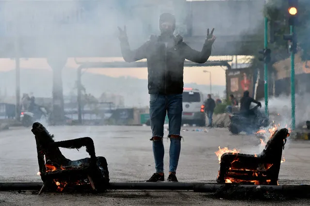A protester flashes the victory sign as demonstrators supporting outgoing Lebanese Prime Minister Hariri block a main highway by burning tires and dumpsters in protest against the nomination of Hassan Diab as Prime Minister, in Beirut, Lebanon, 23 December 2019. The newly appointed Lebanese prime minister vowed on 19 December to form a government of experts within six weeks. (Photo by Wael Hamzeh/EPA/EFE)