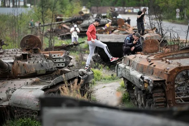 People photograph and inspoect destroyed Russian main battle tanks and armoured vehicles laying beside a road on May 25, 2022 in Irpin, Ukraine. As Russia concentrates its attack on the east and south of the country, residents of the Kyiv region are returning to assess the war's toll on their communities. The towns around the capital were heavily damaged following weeks of brutal war as Russia made its failed bid to take Kyiv. (Photo by Christopher Furlong/Getty Images)