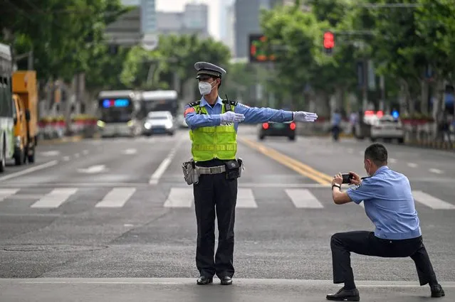An officer takes a pictures of another officer while controlling the traffic in the Jing'an district of Shanghai on June 1, 2022, after the end of the lockdown that kept the city two months with heavy-handed restrictions. (Photo by Hector Retamal/AFP Photo)