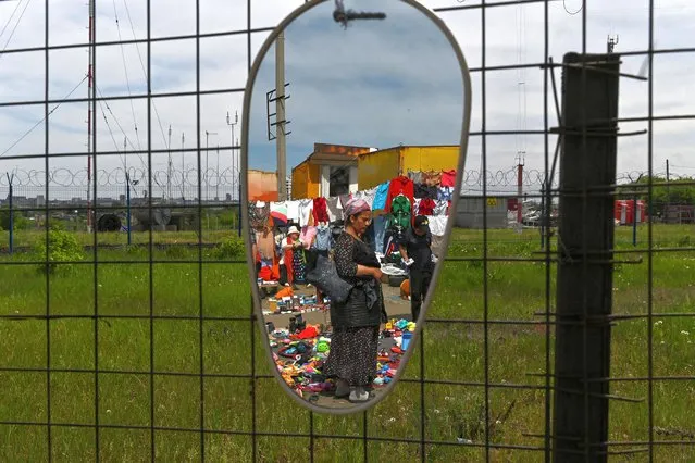 People are reflected in a mirror at a local flea market in Omsk, Russia on May 28, 2022. (Photo by Alexey Malgavko/Reuters)