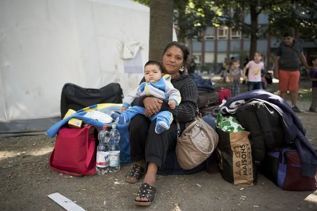 A newly arrived migrant holds her child as she waits to apply for asylum at the State Office for Health and Social Affairs in Berlin, Germany August 10, 2015. (Photo by Stefanie Loos/Reuters)