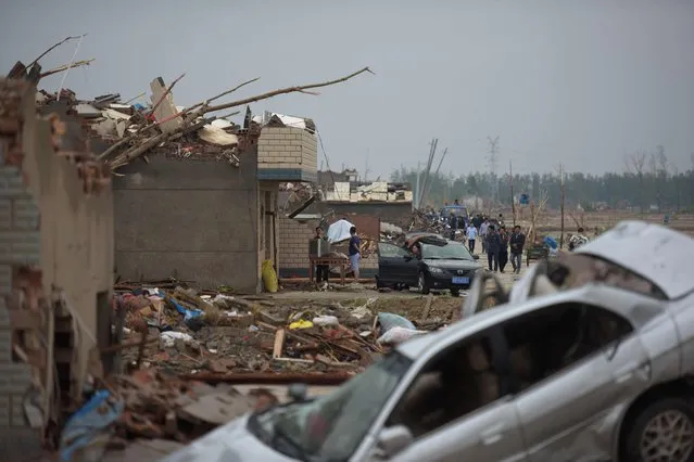 Residents walk next to the rubble of destroyed houses after a tornado in Funing, in Yancheng, in China's Jiangsu province on June 24, 2016. Extreme weather, including hailstorms, heavy rain and a tornado, killed 78 and injured dozens in China's eastern Jiangsu province, the official Xinhua news agency reported on June 23. (Photo by Johannes Eisele/AFP Photo)