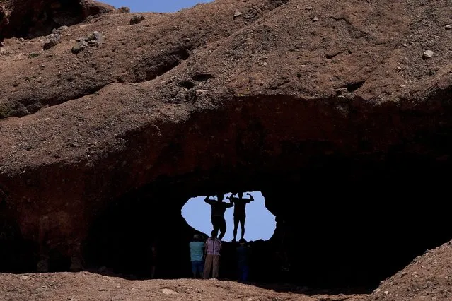 A pair of mid-day hikers pose for a picture in the hole in the rock at Papago Park, Friday, June 10, 2022, in Phoenix. Heat is part of the normal routine of summertime in the desert, but weather forecasters say that doesn't mean people should feel at ease. Excessive heat causes more deaths in the U.S. than other weather-related disasters, including hurricanes, floods and tornadoes combined. Officials are advising people to limit time outdoors, drink plenty of water and seek shade if they must be outside. (Photo by Matt York/AP Photo)
