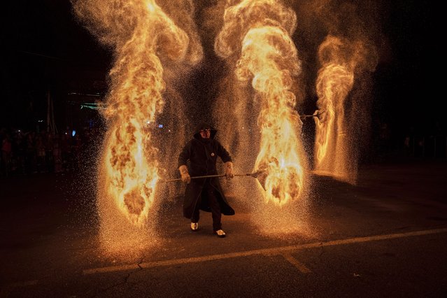 A Chinese performer stands in flames during a traditional molten fire performance at a market during the Golden Week holiday on October 3, 2024 in Beijing, China. China marked its National Day and the 75th anniversary of the founding of the Peoples Republic on October 1st. (Photo by Kevin Frayer/Getty Images)