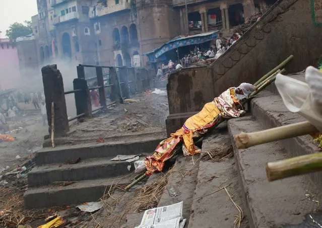 A body is left to dry prior to cremation on the banks of river Ganges in Varanasi, in the northern Indian state of Uttar Pradesh, June 19, 2014. (Photo by Danish Siddiqui/Reuters)