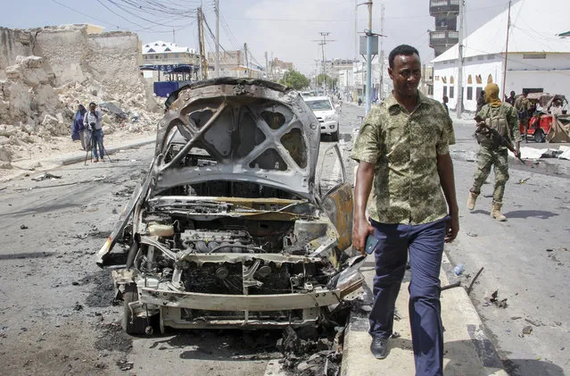 Security forces and others walk past the wreckage of vehicles after a vehicle bomb attack on a security checkpoint located near the presidential palace, in Mogadishu, Somalia, Wednesday, January 8, 2020. (Photo by Farah Abdi Warsameh/AP Photo)