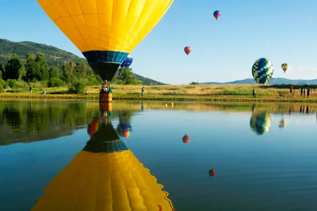 A balloon dips into Bald Eagle lake during the 36th Annual Hot Air Balloon Rodeo in Steamboat Springs, Colorado on July 9, 2017. (Photo by Jason Connolly/AFP Photo)