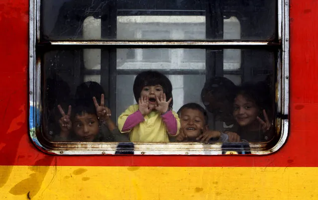 Children migrants look from a window onboard a train departing towards Serbia, at the railway station in the southern Macedonia's town of Gevgelija, on Saturday, August 22, 2015. (Photo by Boris Grdanoski/AP Photo)