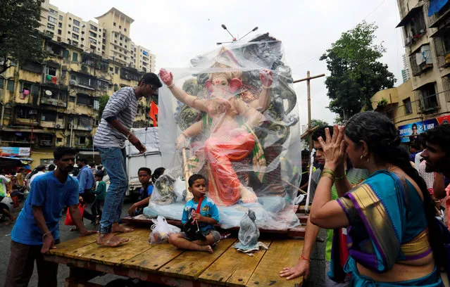 Devotees transport an idol of the Hindu god Ganesh, the deity of prosperity, on a handcart to a place of worship on the first day of the ten-day-long Ganesh Chaturthi festival in Mumbai, India August 25, 2017. (Photo by Danish Siddiqui/Reuters)