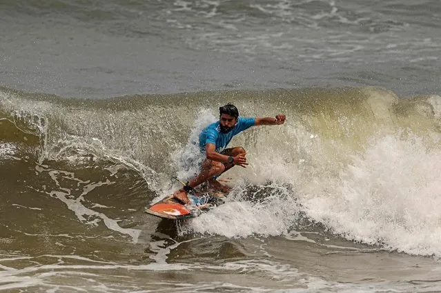 A Palestinian surfer rides a wave in Gaza City on June 22, 2022. (Photo by Mahmud Hams/AFP Photo)