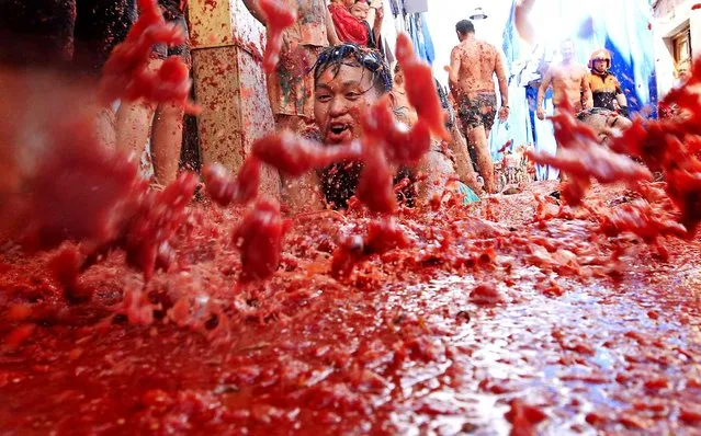 People lie in a puddle of squashed tomatoes, during the annual “Tomatina” tomato fight fiesta, in the village of Bunol, 50 kilometers outside Valencia, Spain, Wednesday, August 26, 2015. (Photo by Alberto Saiz/AP Phot)