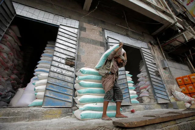A worker carries a sack of wheat flour at a store in Sanaa, Yemen, July 13, 2016. (Photo by Mohamed al-Sayaghi/Reuters)