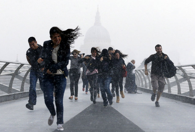 Pedestrians dash through a sudden downpour along the Millennium Bridge, with St. Paul's Cathedral in the background, as the remnants of Hurricane Bertha sweep across parts of the country, London, Sunday, August 10, 2014. (Photo by Jonathan Brady/AP Photo/PA Wire)