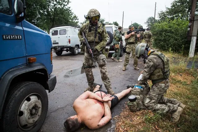 Armed Ukrainian forces detain a pro-Russian militant in the village of Chornukhine in the Lugansk region on August 18, 2014. A Ukrainian warplane was blown out of the sky over rebel-held territory as fierce clashes between government troops and pro-Russian insurgents left dozens of civilians dead. At least 415,800 people have fled their homes due to fighting between government forces and pro-Russian separatists in eastern Ukraine, the UN refugee agency said on August 20. (Photo by Oleksandr Ratushniak/AFP Photo)