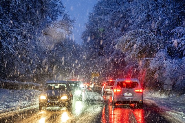 Commuters queue in heavy snowfalls on a country road in a forest of the Taunus region near Frankfurt, Germany, early Tuesday, November 28, 2023. (Photo by Michael Probst/AP Photo)