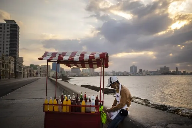 A slushy street vendor, who uses a protective face mask when he has customers as a precaution against the spread of the new coronavirus, waits for them along the seawall, normally bustling with pedestrians, in Havana, Cuba, Friday, March 20, 2020. (Photo by Ramon Espinosa/AP Photo)
