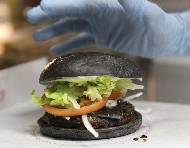 In this September 16, 2014 file photo, Burger King's new menu Kuro Diamond burger is prepared by employee Rumi Sekine at its Shibuya restaurant in Tokyo. (Photo by Koji Sasahara/AP Photo)