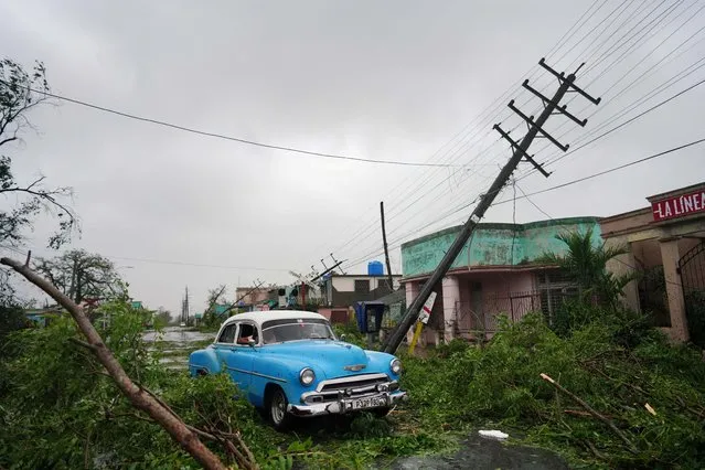 A vintage car passes by debris caused by the Hurricane Ian as it passed in Pinar del Rio, Cuba on September 27, 2022. (Photo by Alexandre Meneghini/Reuters)