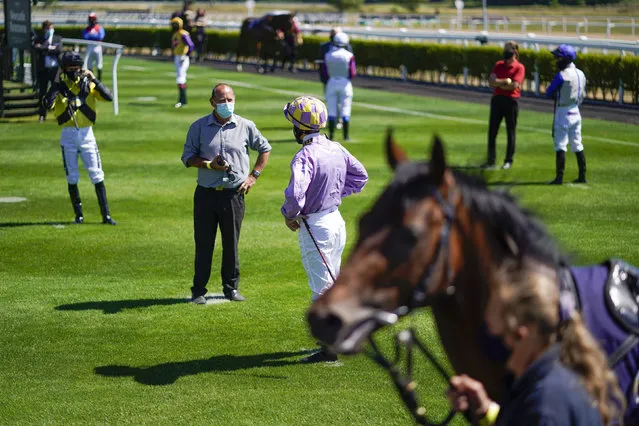 Jockeys observe social distancing as they stand in the paddock before a race as horse racing is resumed at Newcastle Racecourse, in Newcastle, England, Monday June 1, 2020. Horse Racing in the UK returned to action on Monday, but resuming without spectator racegoers following the coronavirus shutdown. (Photo by Alan Crowhurst/PA Wire via AP Photo)