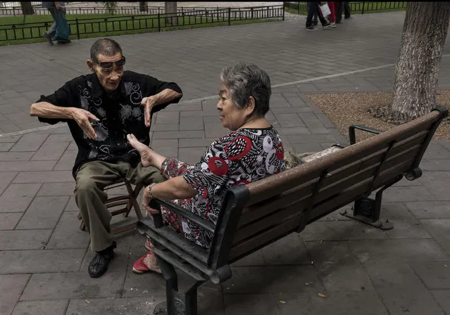 A Chinese man gestures while massaging the feet and trimming the nails of a woman at Beihai Lake area on September 12, 2014 in Beijing, China. (Photo by Kevin Frayer/Getty Images)