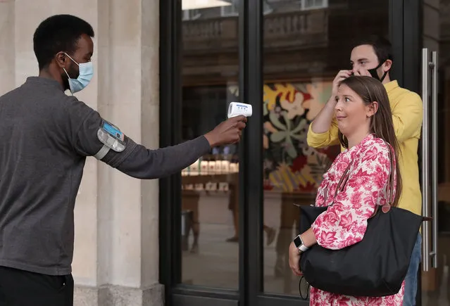 A woman reacts as she gets her temperature checked outside the Apple store in Covent Garden on June 15, 2020 in London, United Kingdom. The British government have relaxed coronavirus lockdown laws significantly from Monday June 15, allowing zoos, safari parks and non-essential shops to open to visitors. Places of worship will allow individual prayers and protective face-masks become mandatory on London Transport. (Photo by Dan Kitwood/Getty Images)