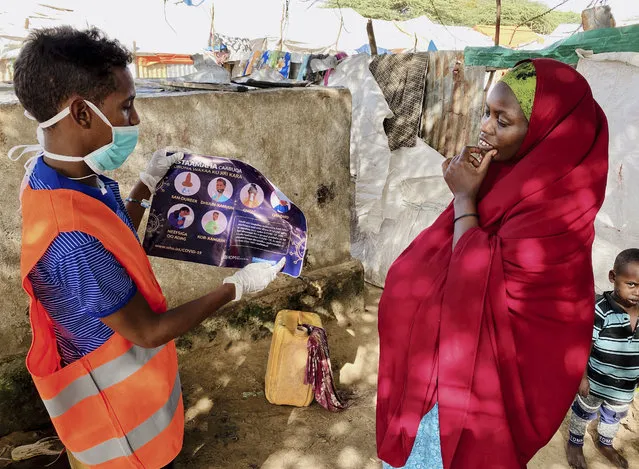 In this photo taken Wednesday, June 10, 2020, an internally-displaced Somali woman, right, is informed how to protect herself from the coronavirus, at the Weydow IDP camp in Mogadishu, Somalia. A half-year into the most momentous pandemic in decades, it's hard to imagine that anyone, anywhere hasn't heard of the coronavirus but hundreds of migrants arriving in Somalia are proving some people are still unaware of COVID-19. (Photo by Hamza Osman/International Organization for Migration (IOM) – Somalia via AP Photo)