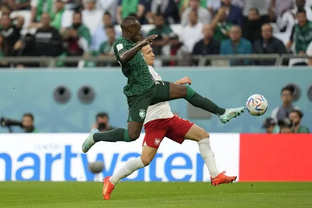 Saudi Arabia's Saud Abdulhamid, foreground, fights for the ball with Poland's Przemyslaw Frankowski during the World Cup group C soccer match between Poland and Saudi Arabia, at the Education City Stadium in Al Rayyan, Qatar, Saturday, November 26, 2022. (Photo by Francisco Seco/AP Photo)