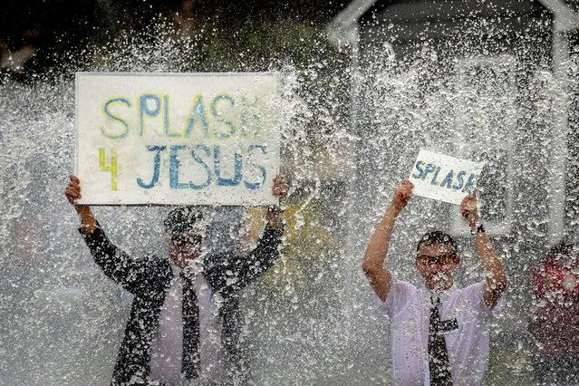 Missionaries and members of the Church of Jesus Christ of Latter-day Saints, Bennet Lim, 21, left, and Jack Bodmer, 18, hold signs as they entice commuters to give them a splash during the first major storm of the year in Chino, Calif. on Thursday, January 5, 2023. (Photo by Watchara Phomicinda/The Orange County Register via AP Photo)