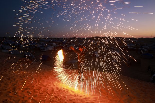 A Palestinian youth plays with a sparkler in Rafah, in the southern Gaza Strip, on the eve of the Muslim holy fasting month of Ramadan on March 10, 2024, amid ongoing battles between Israel and the militant group Hamas. (Photo by Mohammed Abed/AFP Photo)