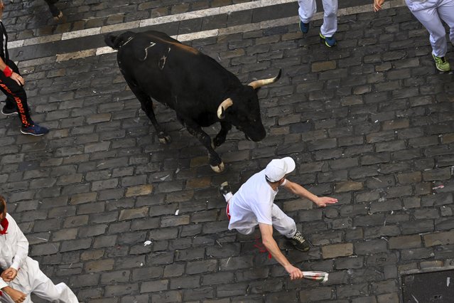 Revelers run with bulls from Fuente Ymbro ranch during the first day of the running of the bulls at the San Fermín fiestas in Pamplona, Spain, Monday, July 7, 2025. (Photo by Miguel Oses/AP Photo)
